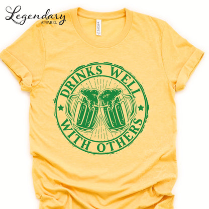 A yellow t-shirt with a graphic design featuring two beer mugs with a text message printed on them.
