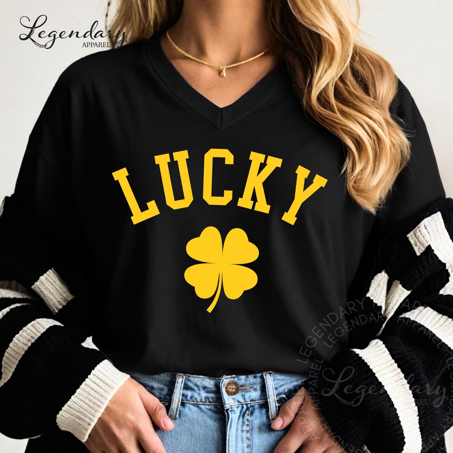 A woman wearing a black t-shirt with the word "Lucky" printed on it, along with a yellow clover symbol. She is also wearing a black and white striped sweater.