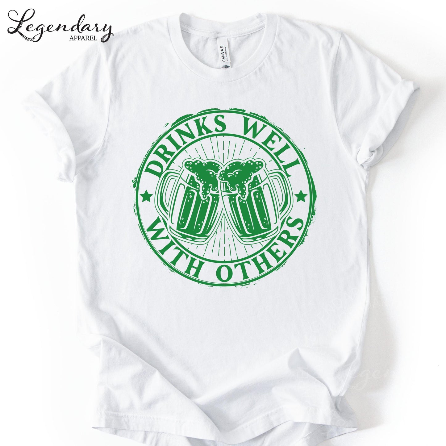 A white t-shirt with a green circular graphic design that says "DRINKS WELL WITH OTHERS" and features two beer mugs with foam on top.