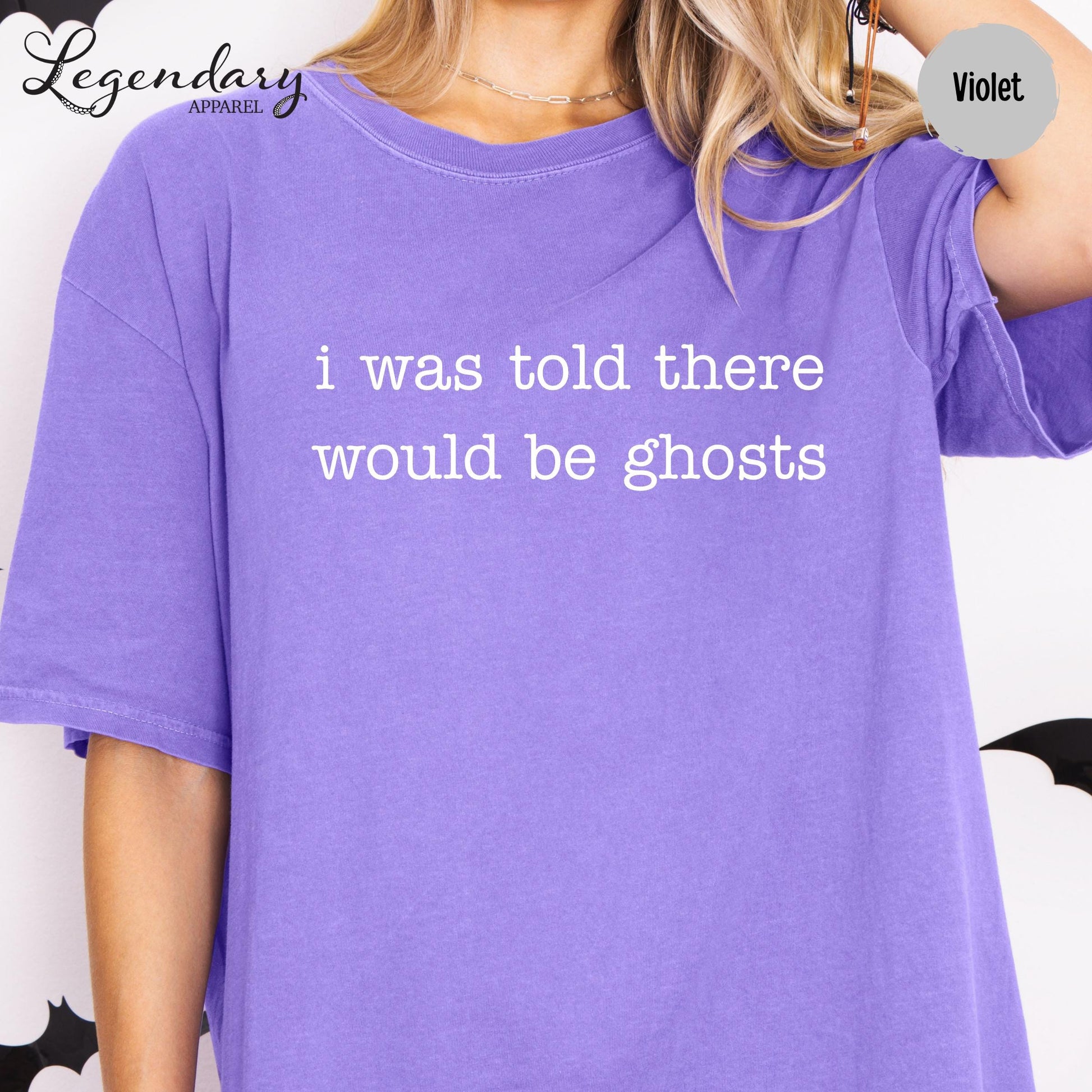 A person wearing a purple t-shirt with the text "I was told there would be ghosts" printed on it.