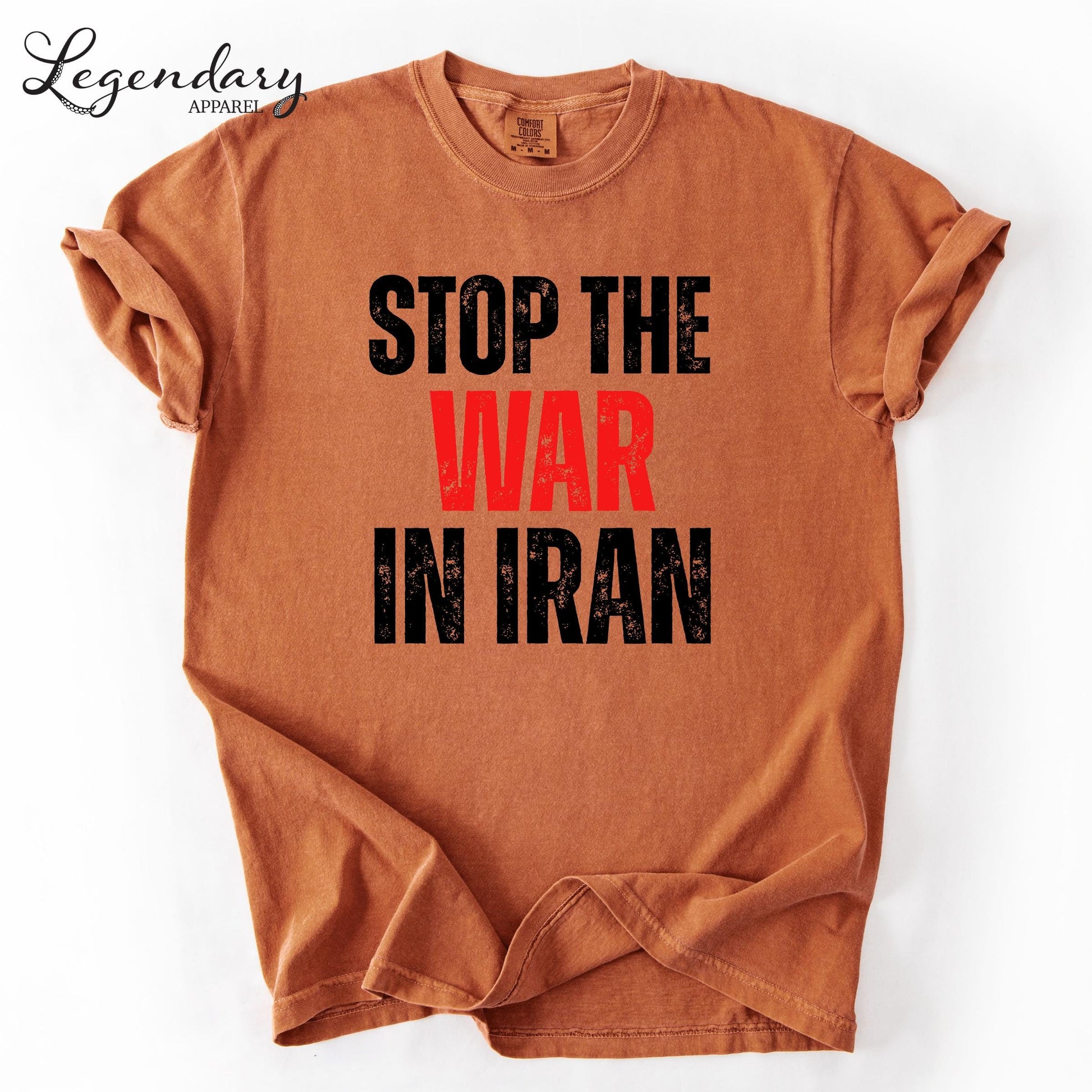 a brown t-shirt with the text "STOP THE WAR IN IRAN" printed on it in a bold, red font.