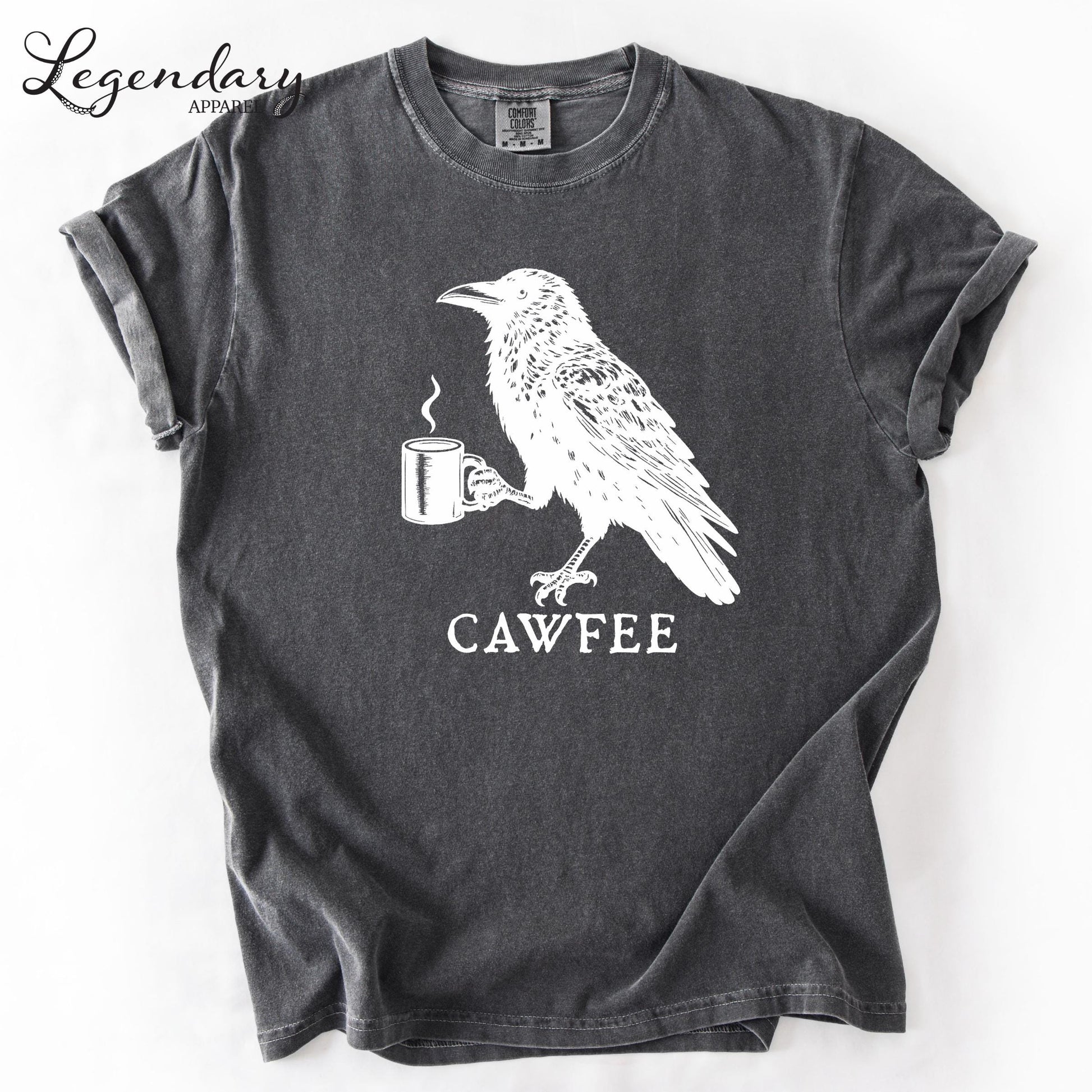 The image is a gray t-shirt with a white graphic design depicting a bird holding a cup of coffee. The text "CAWFEE" is printed below the bird and cup.