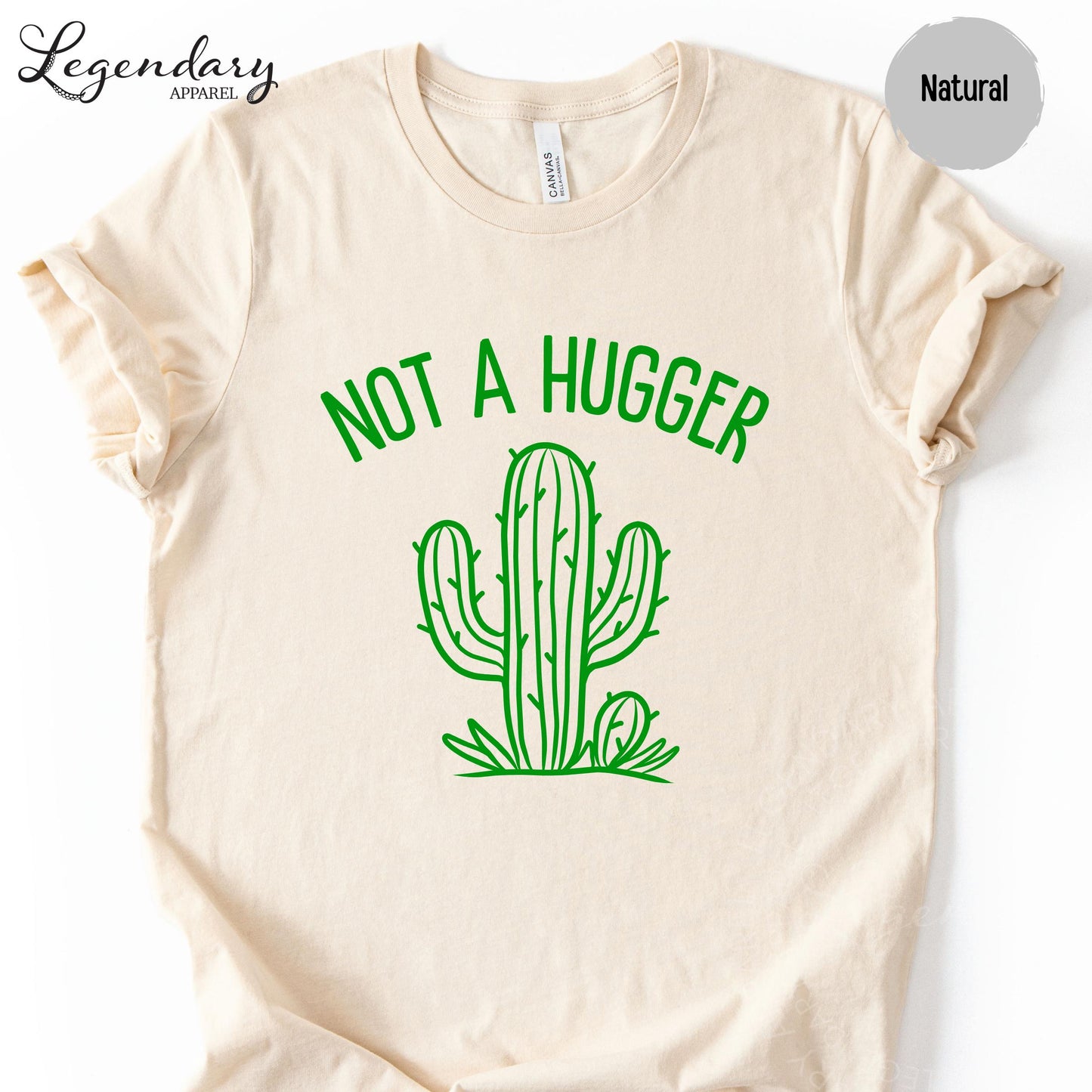 A beige t-shirt with a green graphic design depicting a cactus and the text "NOT A HUGGER" printed on it.