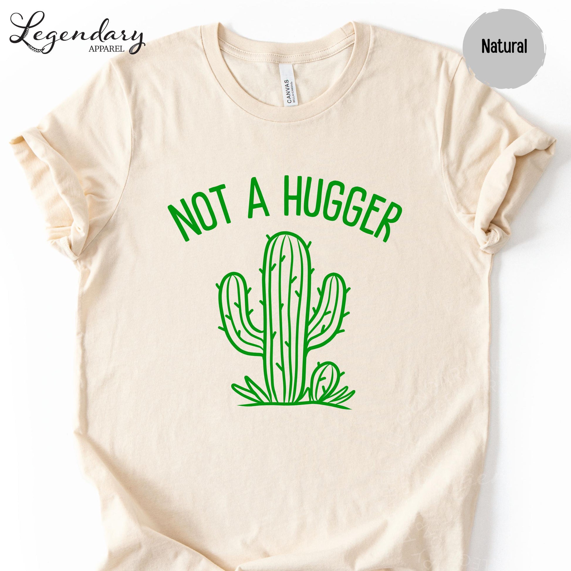 A beige t-shirt with a green graphic design depicting a cactus and the text "NOT A HUGGER" printed on it.