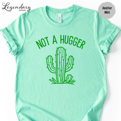 A mint green t-shirt with a graphic of a cactus and the text "NOT A HUGGER" printed on it.