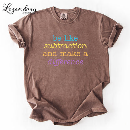 A brown t-shirt with the text "be like subtraction and make a difference" printed on it.