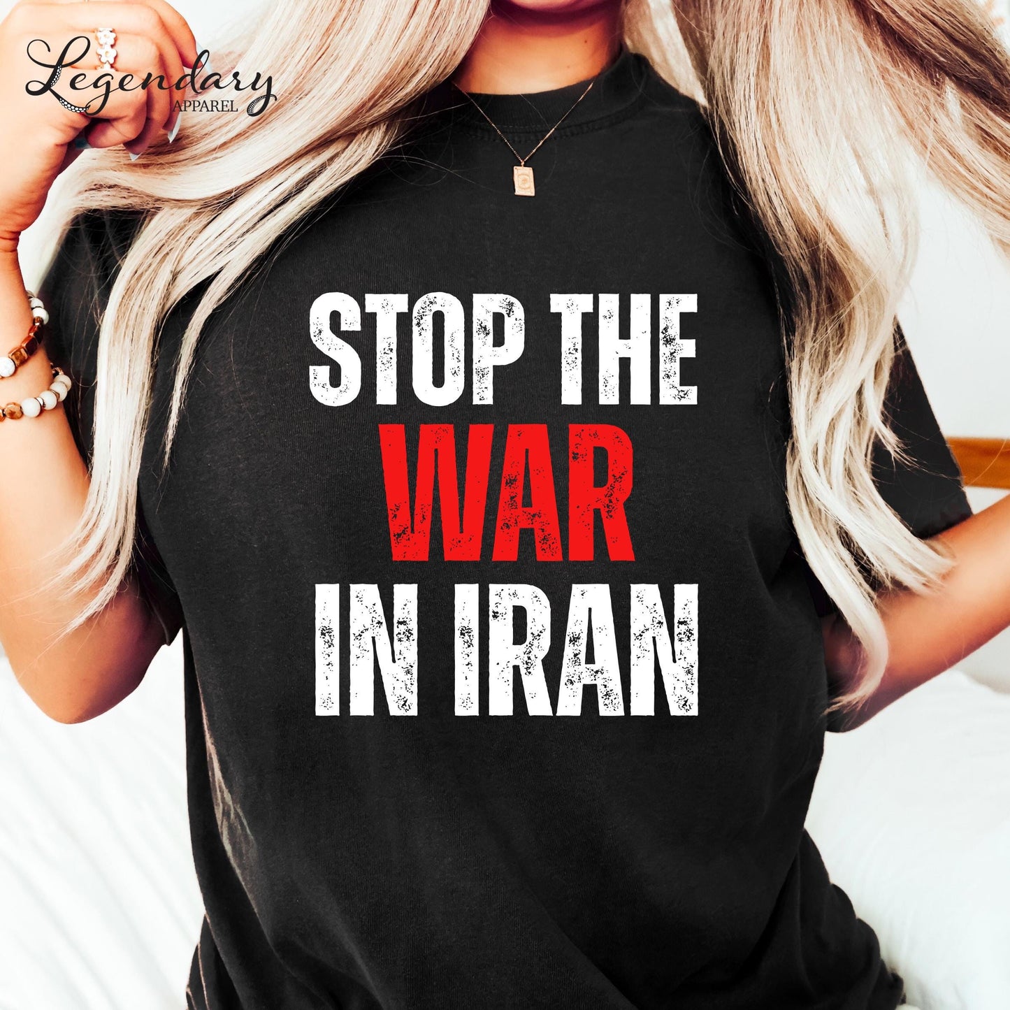 A person wearing a black t-shirt with the text "STOP THE WAR IN IRAN" printed on it.