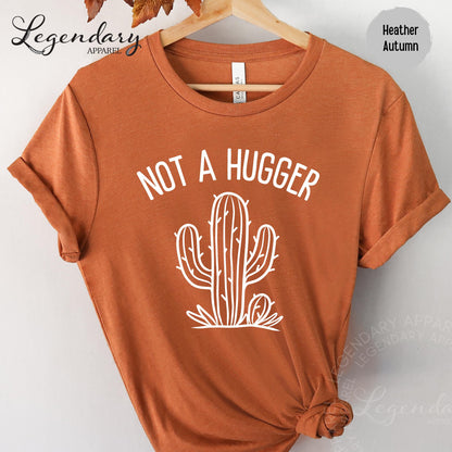 a red t-shirt with a white graphic design on it, which includes a cactus and the text "NOT A HUGGER".