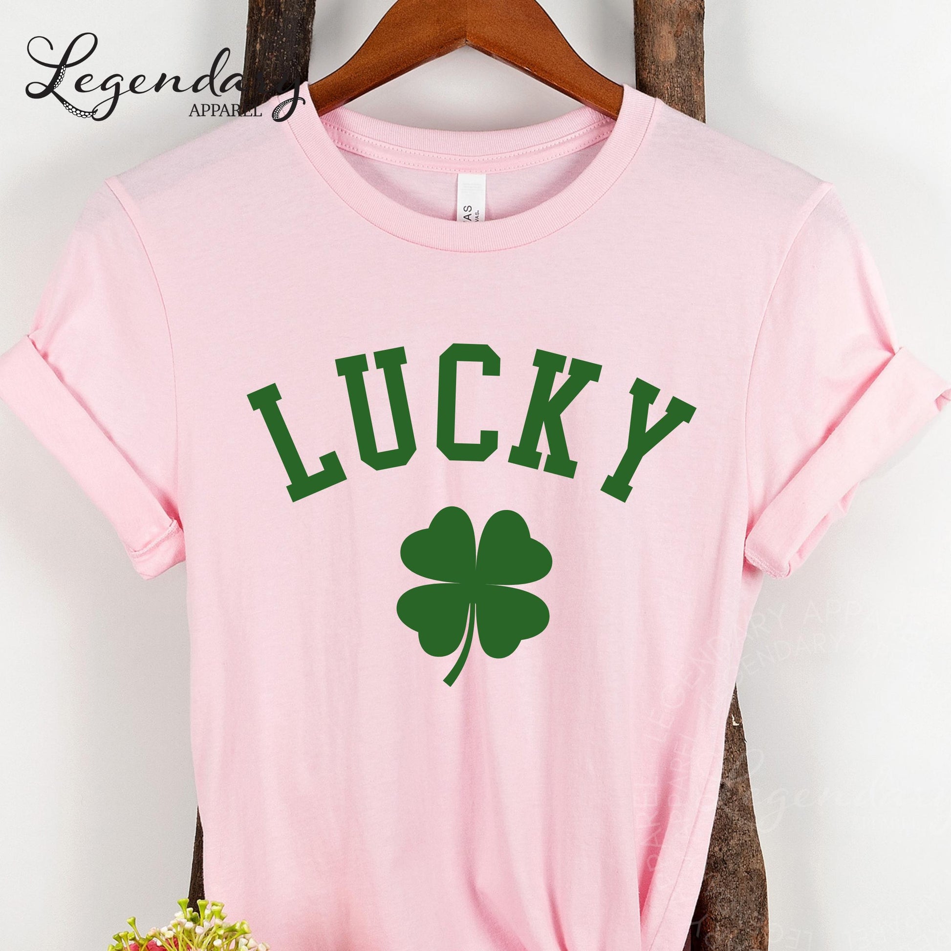 A pink t-shirt with the word "Lucky" printed on it, along with a green clover symbol.