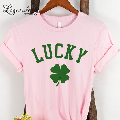 A pink t-shirt with the word "Lucky" printed on it, along with a green clover symbol.
