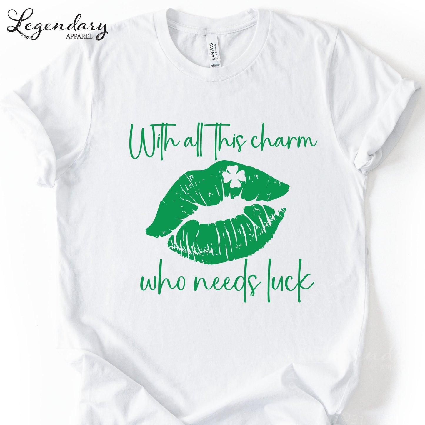A white t-shirt with a graphic design featuring green lips with a clover on them, along with the text "With all this charm who needs luck".