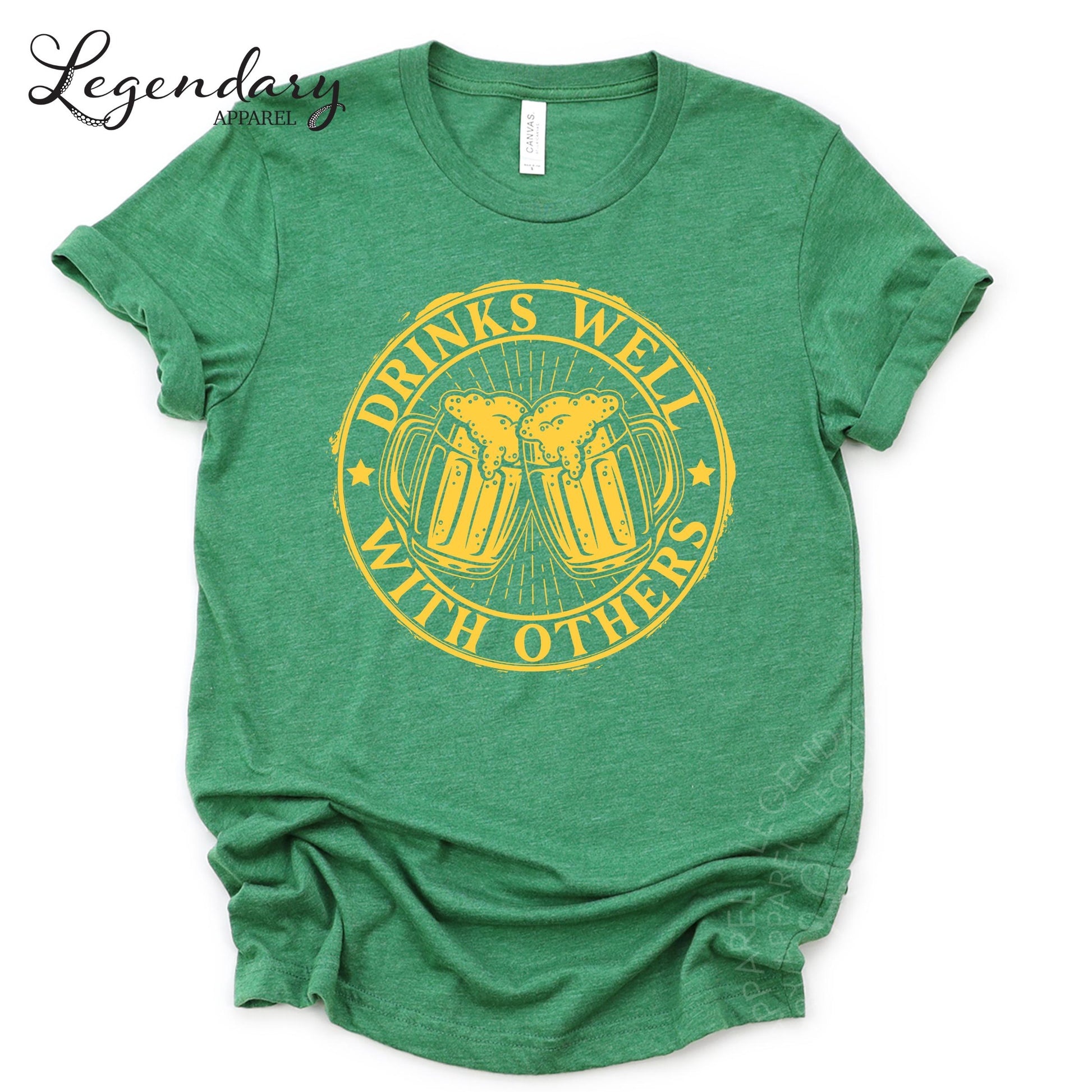 A green t-shirt with a graphic design that says "Drinks well with others" in yellow text.