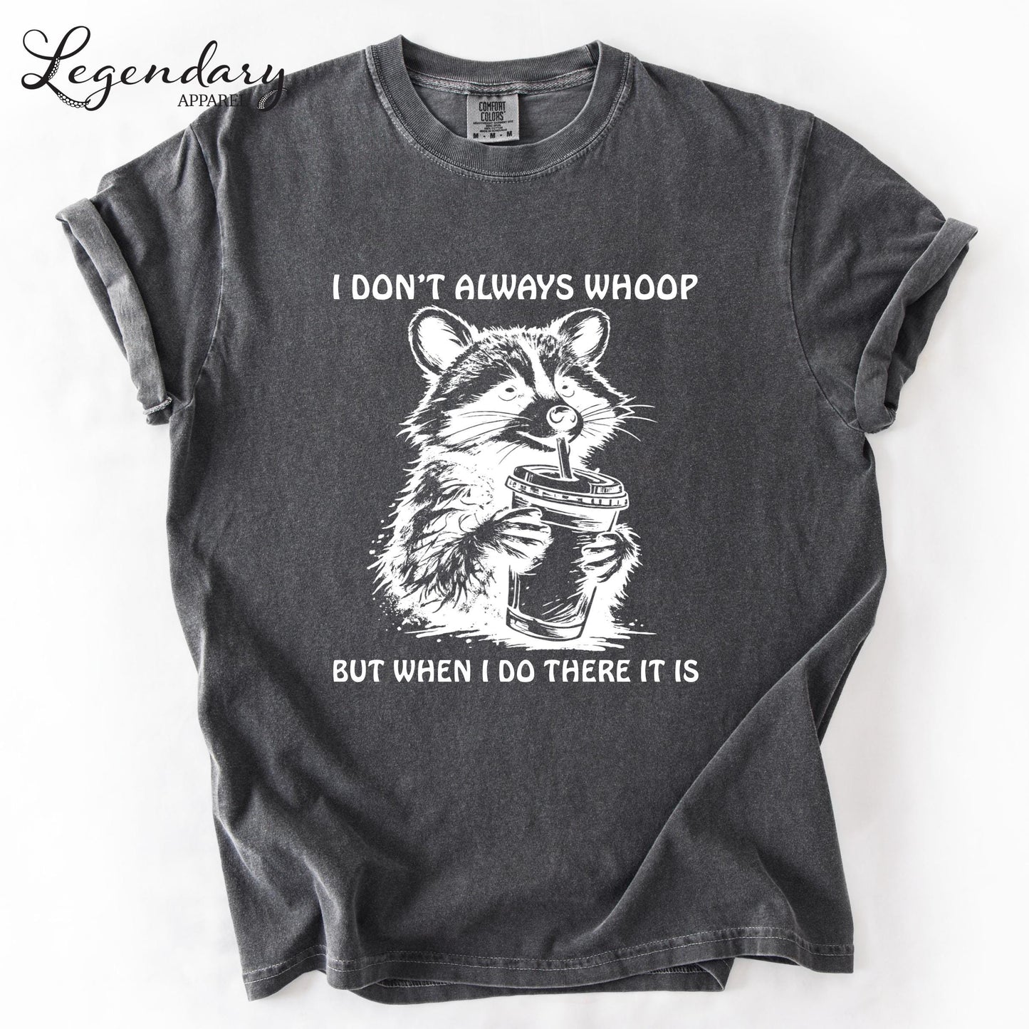 A gray t-shirt with a graphic design depicting a raccoon holding a cup and the text "I DON'T ALWAYS WHOOP BUT WHEN I DO THERE IT IS" printed on it.