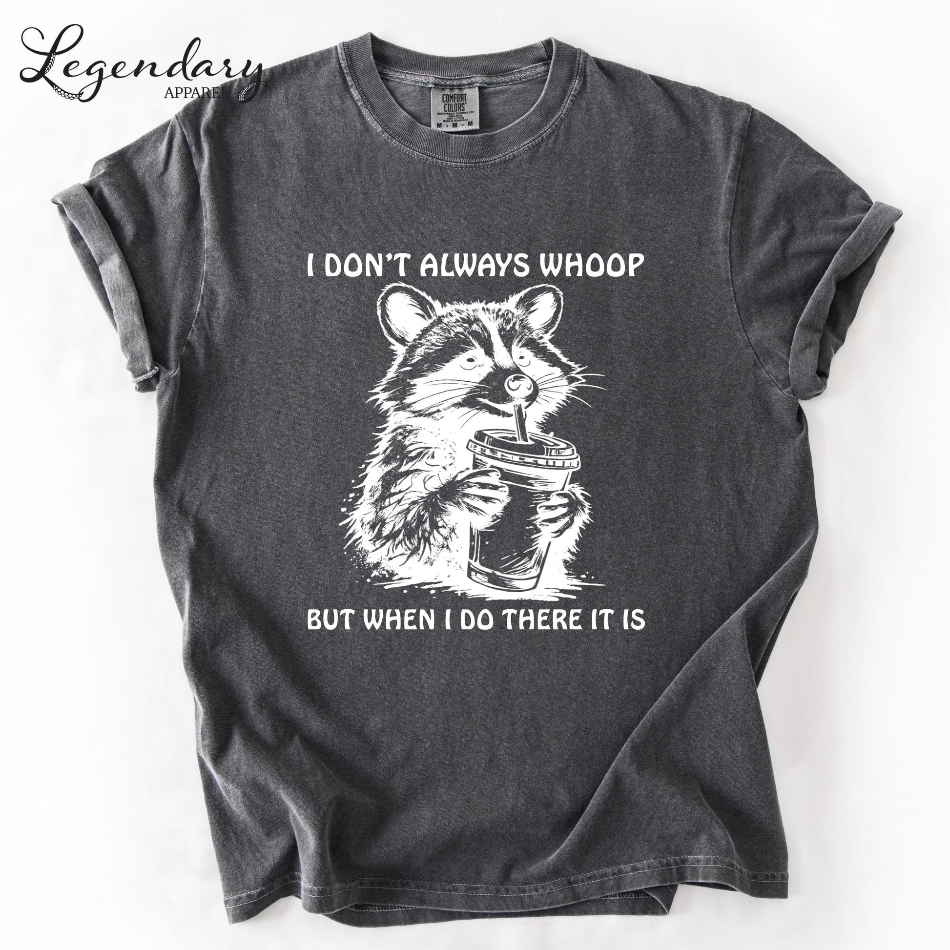 A gray t-shirt with a graphic design depicting a raccoon holding a cup and the text "I DON'T ALWAYS WHOOP BUT WHEN I DO THERE IT IS" printed on it.