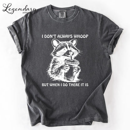 A gray t-shirt with a graphic design depicting a raccoon holding a cup and the text "I DON'T ALWAYS WHOOP BUT WHEN I DO THERE IT IS" printed on it.