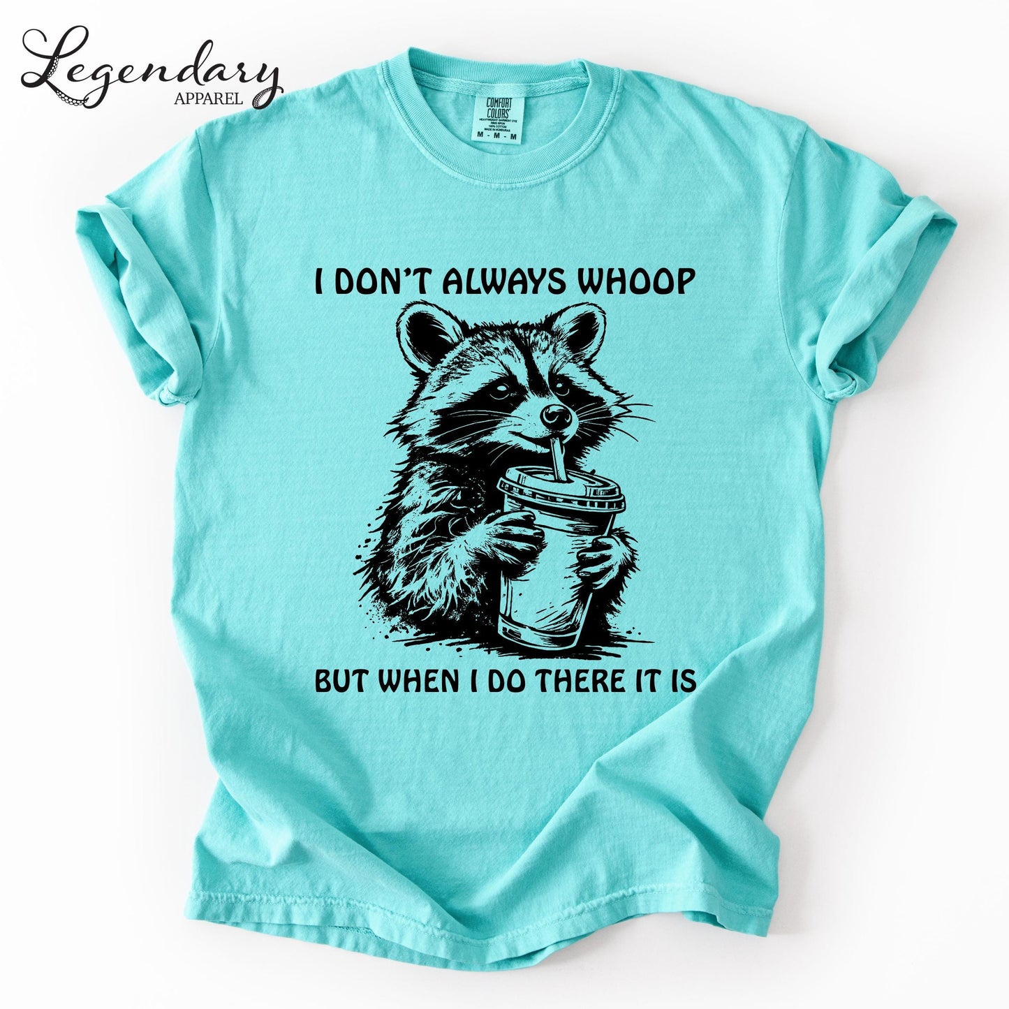 A turquoise t-shirt with a graphic of a raccoon holding a drink and the text "I DON'T ALWAYS WHOOP BUT WHEN I DO THERE IT IS" printed on it.