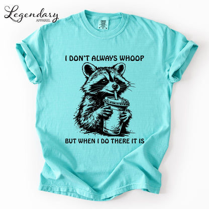 A turquoise t-shirt with a graphic of a raccoon holding a drink and the text "I DON'T ALWAYS WHOOP BUT WHEN I DO THERE IT IS" printed on it.