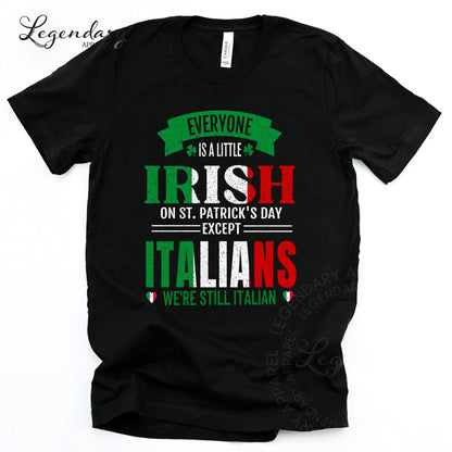 The image is a black t-shirt with a humorous text and graphics design that reads "EVERYONE IS A LITTLE IRISH ON ST. PATRICK'S DAY EXCEPT ITALIANS WE'RE STILL ITALIAN".