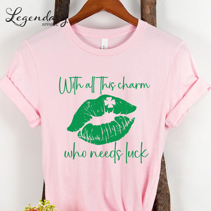 A pink t-shirt with a graphic design of green lips and a white clover, along with the text "With all this charm who needs luck" printed on it.