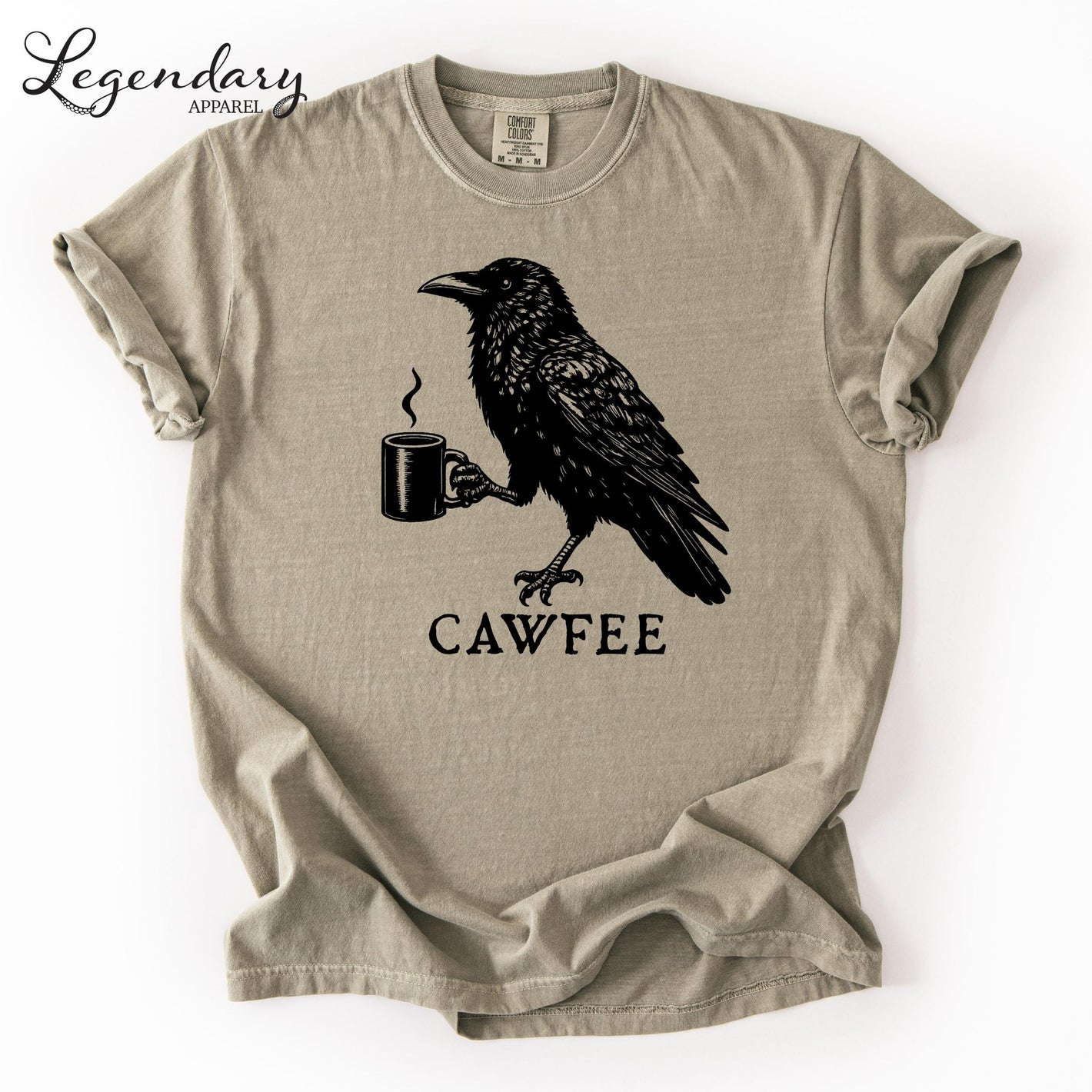 a t-shirt with a black and white graphic design depicting a crow holding a cup of coffee. The text "CAWFE" is printed below the image.