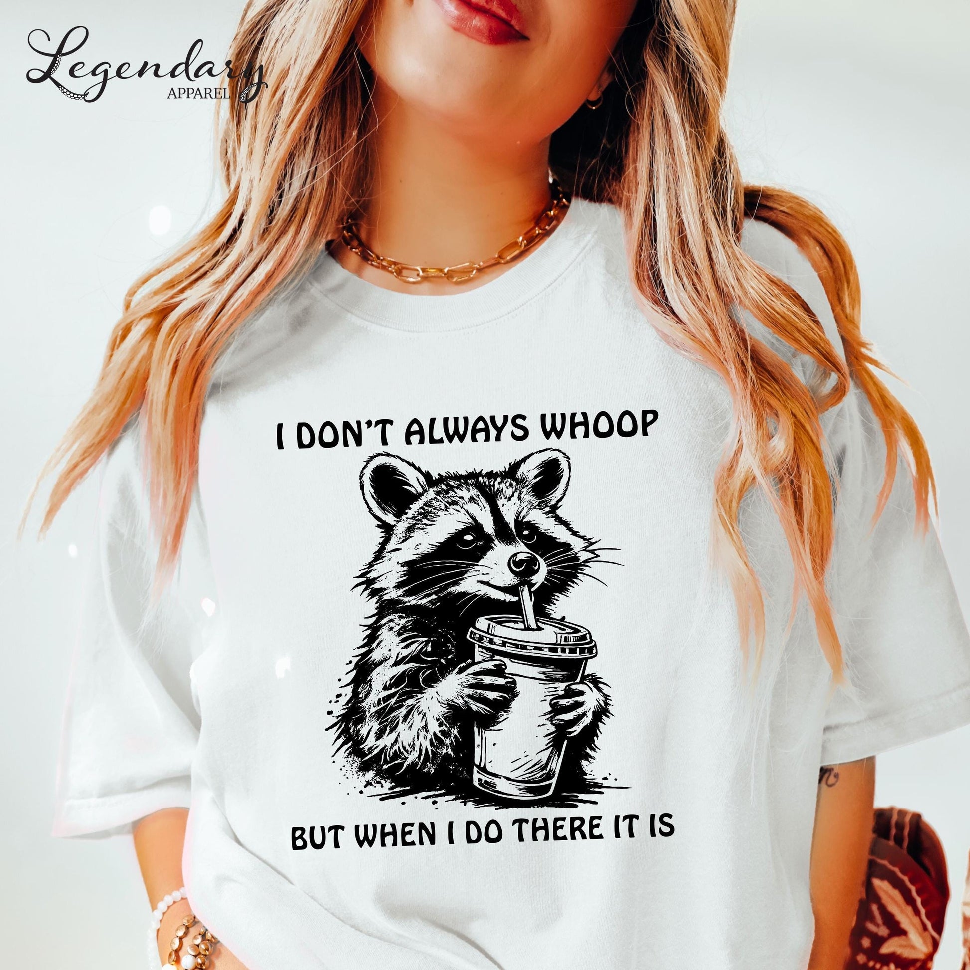 A woman wearing a white t-shirt with a graphic of a raccoon holding a cup and the text "I DON'T ALWAYS WHOOP BUT WHEN I DO THERE IT IS".