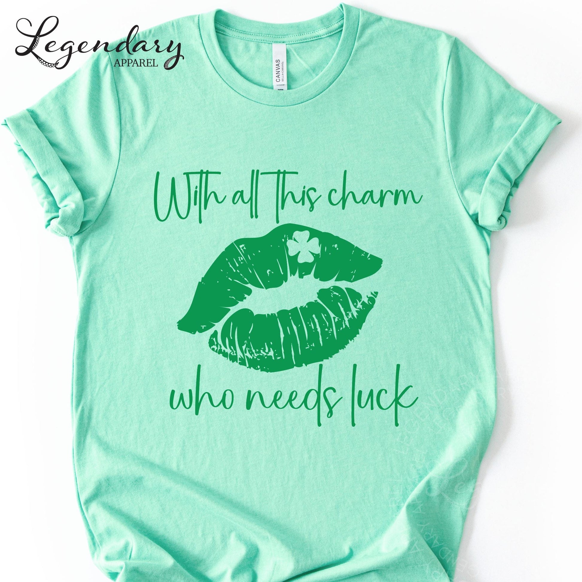 A mint green t-shirt with a graphic design of green lips and a clover on the tongue, along with the text "With all this charm who needs luck".
