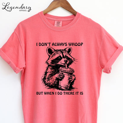 A pink t-shirt with a graphic design of a raccoon holding a cup, accompanied by the text "I DON'T ALWAYS WHOOP BUT WHEN I DO THERE IT IS".