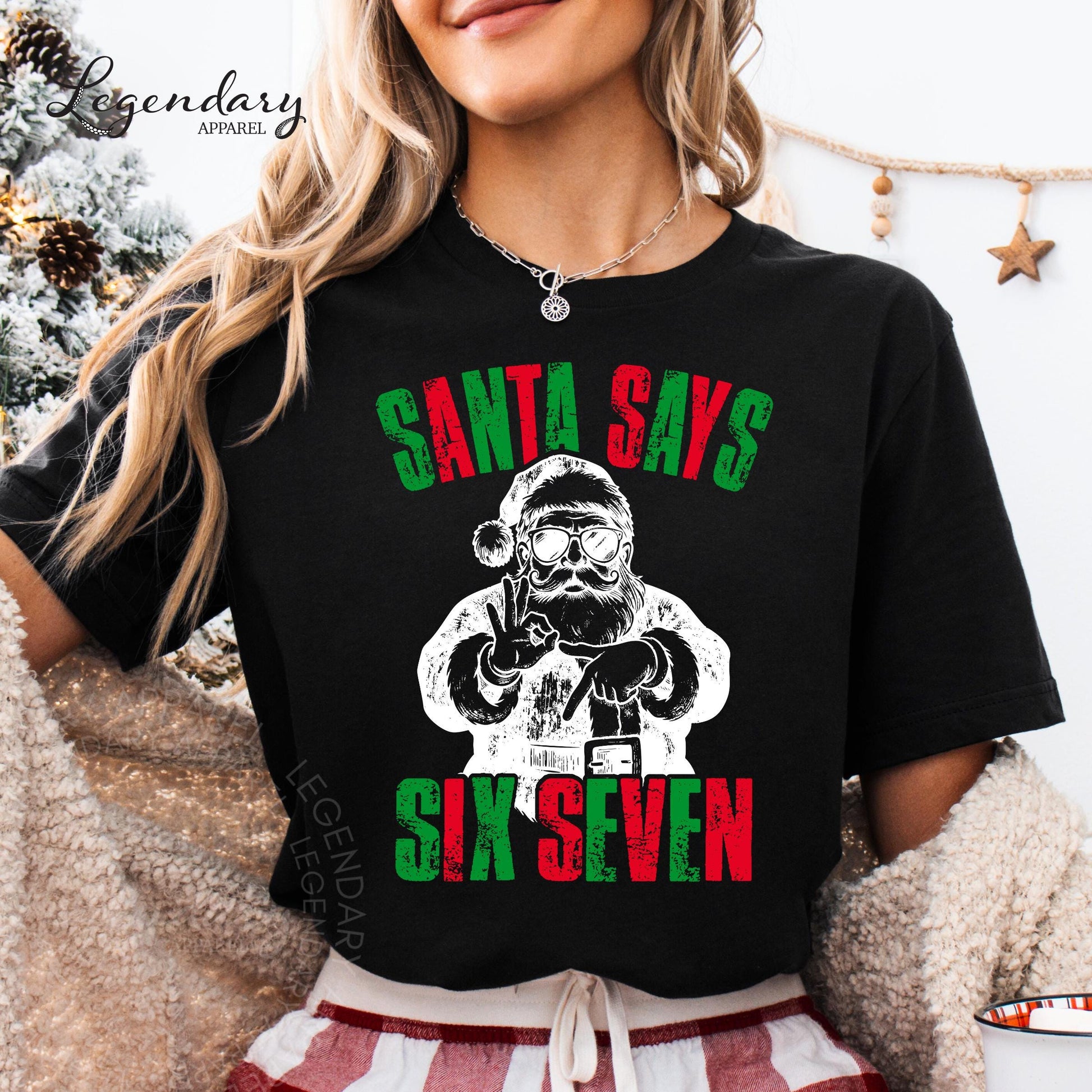 A woman wearing a black t-shirt with a graphic design of Santa Claus and the text &quot;Santa says six seven&quot; printed on it.