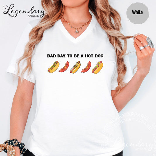 A woman wearing a white t-shirt with a graphic design of hot dogs and the text "Bad day to be a hot dog" printed on it.