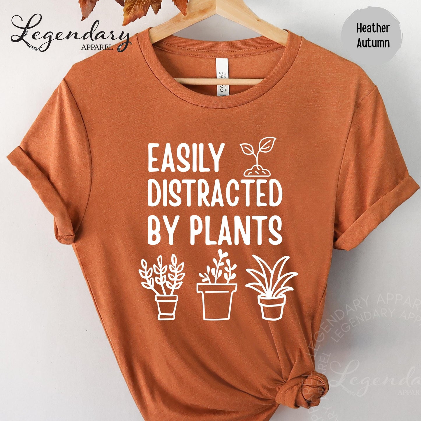 a red t-shirt with a white graphic design that says "EASILY DISTracted BY PLANTS" and includes three potted plants.