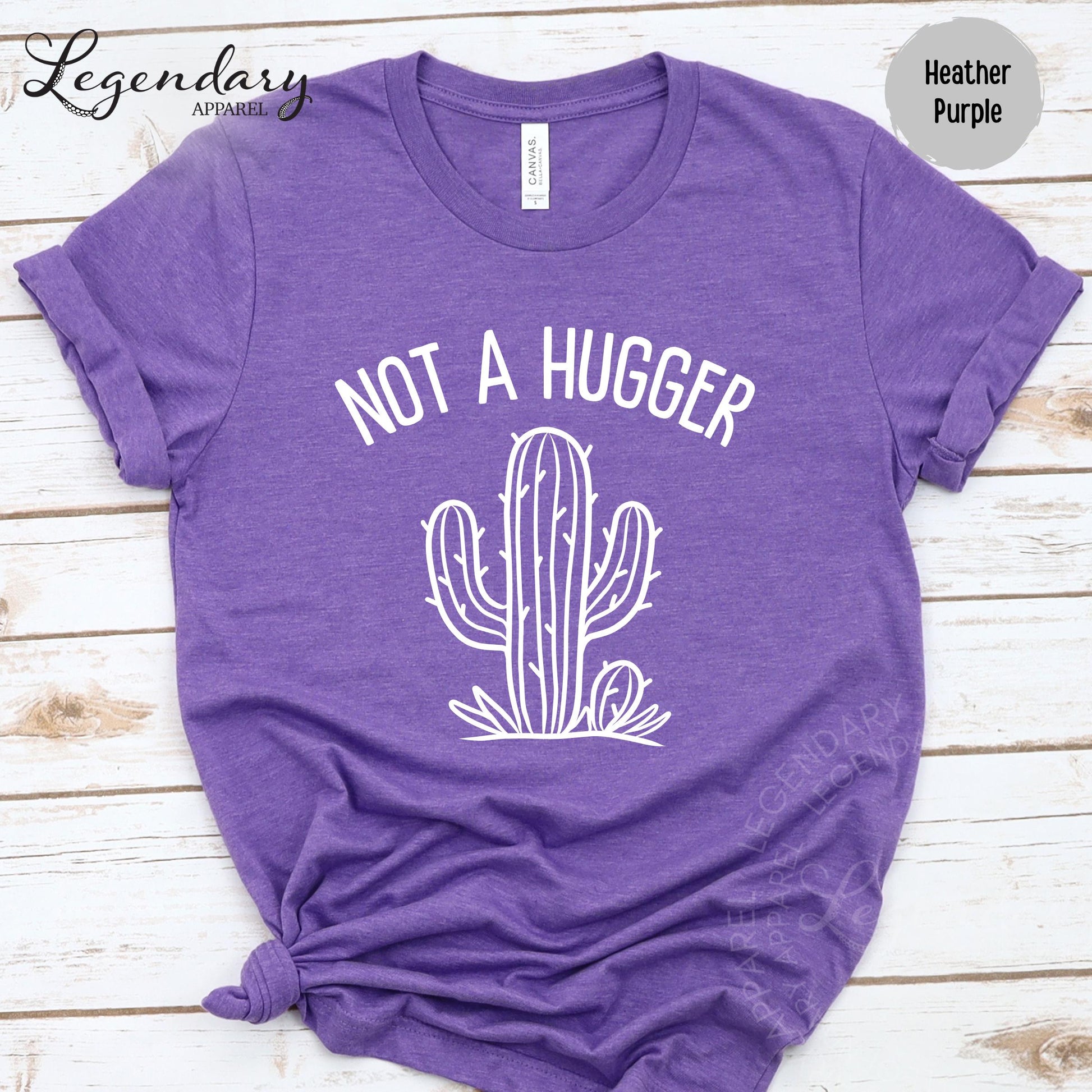 A purple t-shirt with a white graphic design of a cactus and the text "NOT A HUGGER" printed on it.