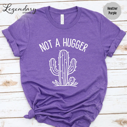 A purple t-shirt with a white graphic design of a cactus and the text "NOT A HUGGER" printed on it.