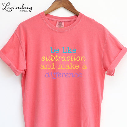 A pink t-shirt with the text "be like subtraction and make a difference" printed on it.