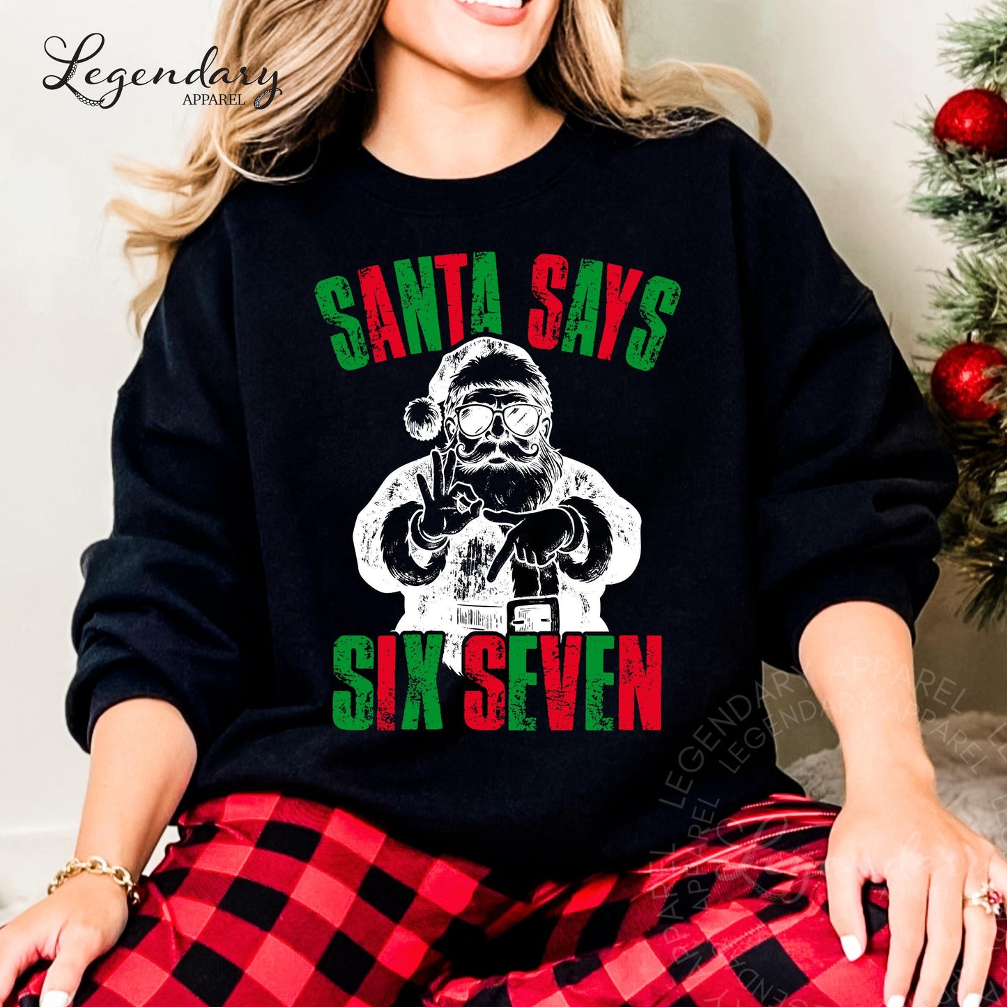 A woman wearing a black sweatshirt with a graphic design of Santa Claus and the text &quot;Santa says six seven&quot; printed on it.